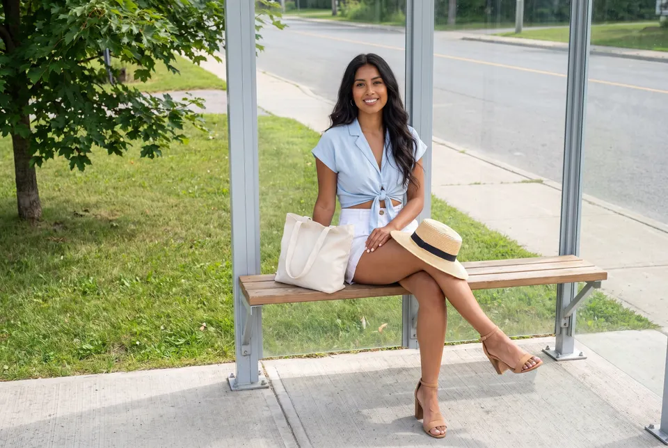 Woman on a bench in a glass bus shelter